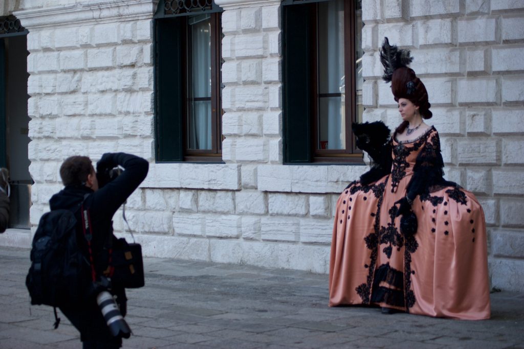 Argazkilari bat mozorratutako emakume bati argazkia egiten ari zaio, Venezian.